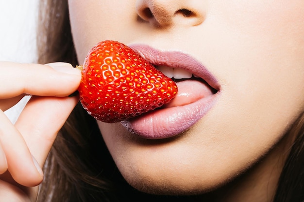 Labbra femminili che mangiano fragola rossa