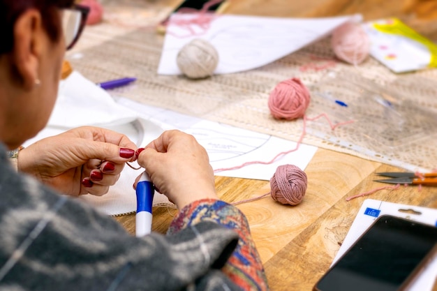 Laboratorio dell'ago del punzone Ricamo dell'ago del punzone Donna anziana che spinge l'ago del punzone verso il basso