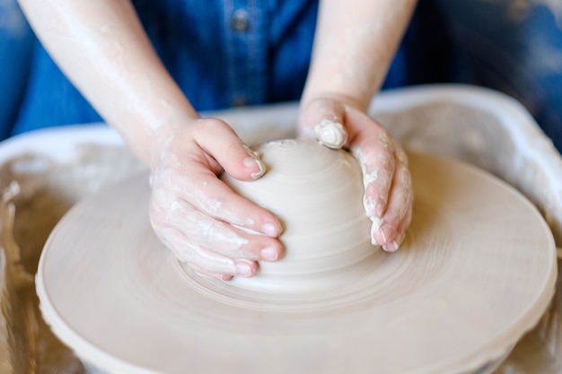 Laboratorio di ceramica. artigianato fatto a mano. artigiano bambino che lavora con l'argilla sulla tornitura del tornio da vasaio.