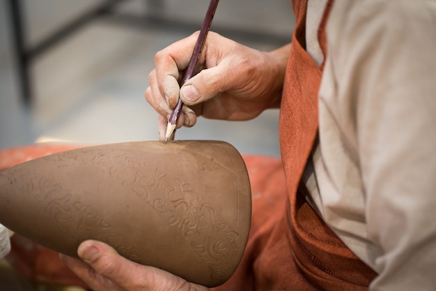 Laboratorio di ceramica, il maestro mette otnament su brocca di terracotta non cotta