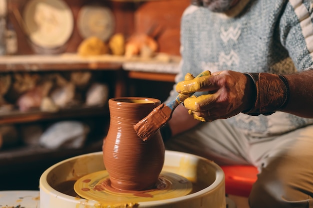 Laboratorio di ceramica. Un uomo anziano fa un vaso di argilla. Modellazione di argilla