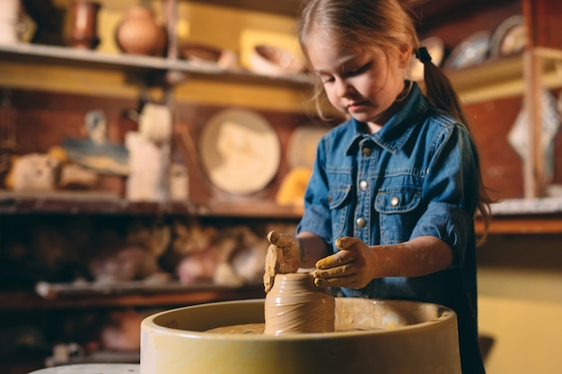 Laboratorio di ceramica. Una bambina fa un vaso di argilla. Modellazione di argilla