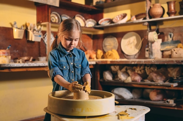 Laboratorio di ceramica. Una bambina fa un vaso di creta. Modellazione in argilla.