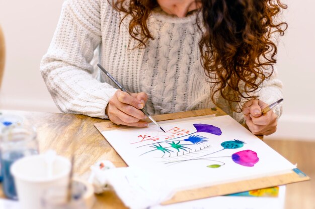 Laboratorio di pittura ad acquerello Pittrice giovane donna che disegna con tavolozza ad acquerello su carta