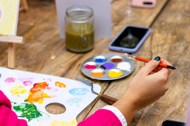 Laboratorio di pittura Primo piano della mano di una donna con chiodi dipinti di nero che tengono un pennello