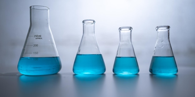 Laboratorio di scienze chimiche con liquido blu nel bicchiere della provetta e attrezzatura di vetreria termine di ricerca di biologia o chimica e medicina esperimento di biotecnologia che lavora su vetro scientifico