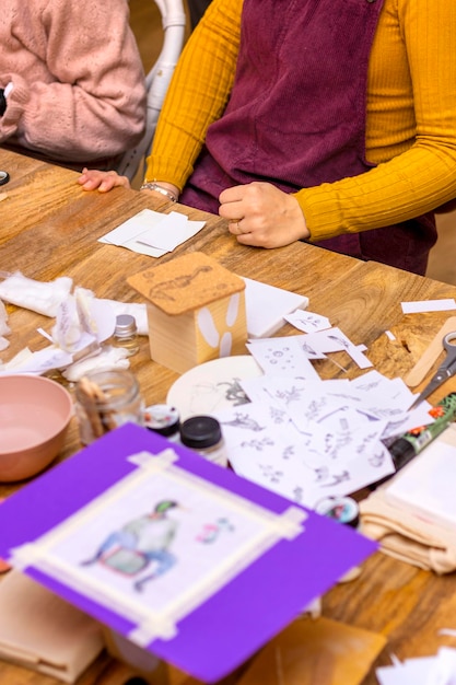 Laboratorio di trasferimento delle immagini Giovane donna in maglione di senape che lavora su un tavolo di legno