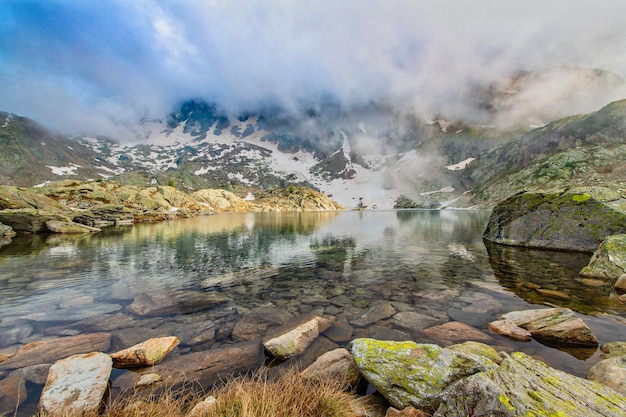 Lago alpino con riflessi di nuvole e cielo