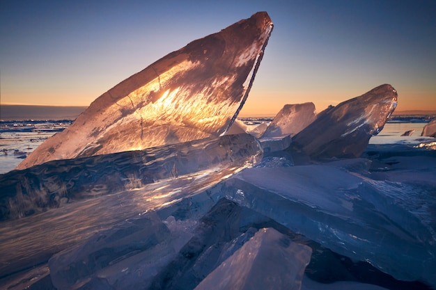 Lago Baikal al tramonto, tutto è coperto di ghiaccio e neve, denso ghiaccio blu chiaro