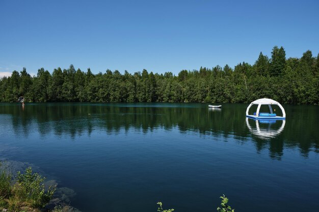 Lago blu chiaro e foresta mista verde Gommone e gazebo in lontananza Ruskeala Mountain Park