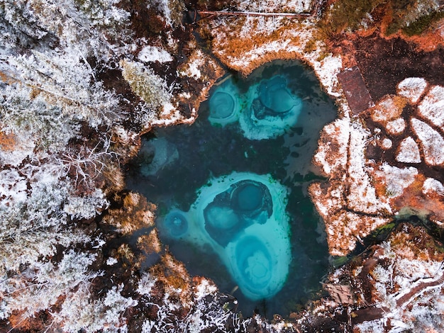 Lago blu del geyser nella foresta di autunno dopo la nevicata Montagne di Altai Russia