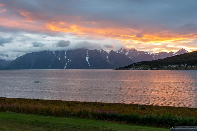 Lago con montagne in barca con neve sullo sfondo con cielo al tramonto rosso