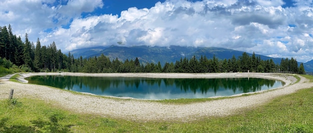 Lago di montagna blu con erba e alberi nuvole cielo blu austria