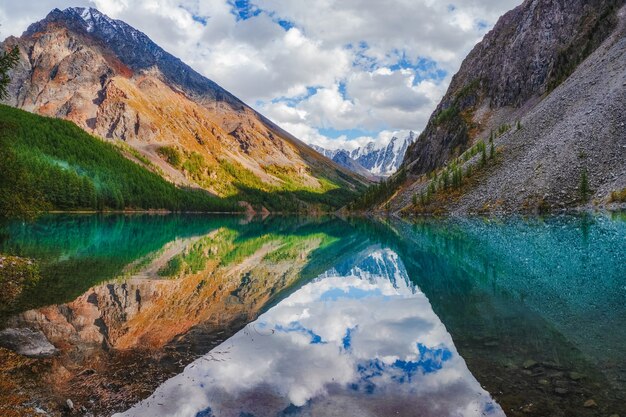 Lago di montagna pittoresco nel giorno drammatico, Altai. Bellissimo riflesso di montagne, cielo e nuvole bianche.