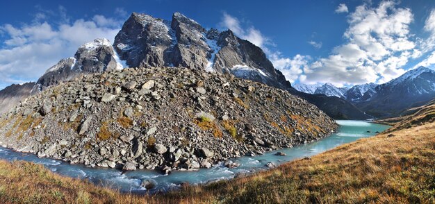 Lago e fiume nei monti Altai, ampia vista, picchi rocciosi nella neve, viaggio in montagna