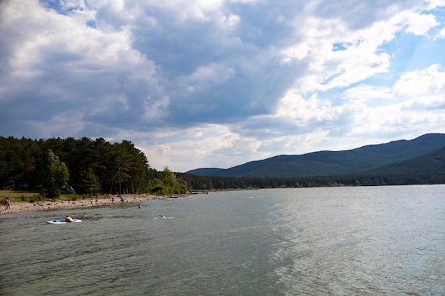 Lago e sullo sfondo c'è una montagna. Spiaggia per il relax in una zona di montagna.