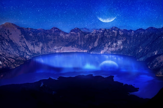 Lago nel cratere di un vulcano sullo sfondo del cielo stellato Riflesso del chiaro di luna sull'acqua Indonesia Vulcano Rinjani