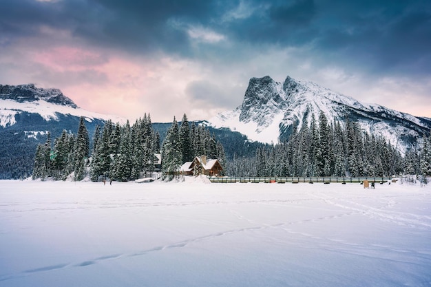 Lago smeraldo con casetta in legno che risplende nella pineta innevata e montagne rocciose in inverno al parco nazionale di Yoho