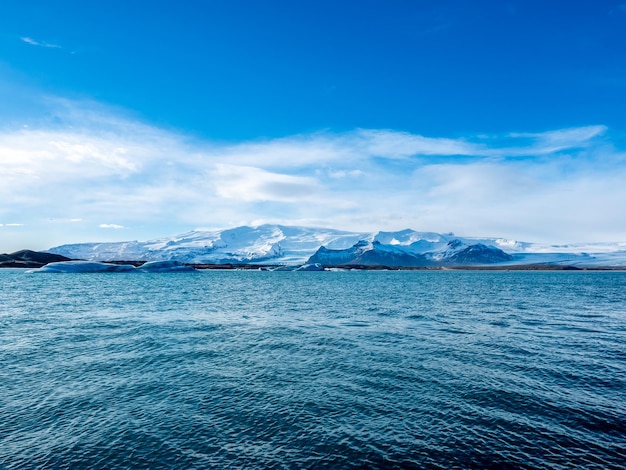 Laguna dell'iceberg di Jokulsarlon con il ghiacciaio e il grande iceberg sotto il cielo blu nuvoloso in Islanda