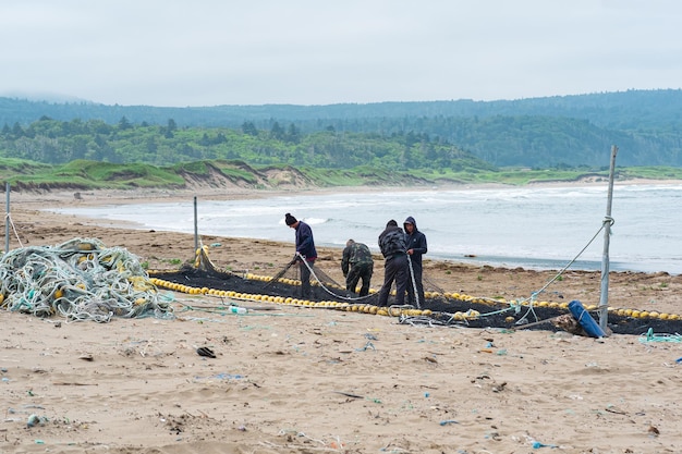 Lagunnoe, Russia - 01 agosto 2022: i pescatori controllano e riparano la rete da pesca sulla riva