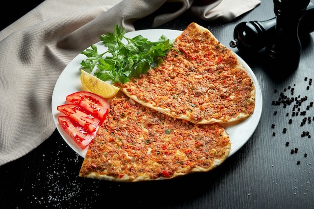 Lahmacun è un popolare piatto turco. Tortilla croccante sottile con agnello tritato, pomodori e peperone sulla tavola nera