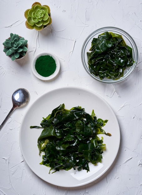 laminaria Alga Kelp e polvere di spirulina con una ciotola in ceramica su sfondo bianco. vista dall'alto