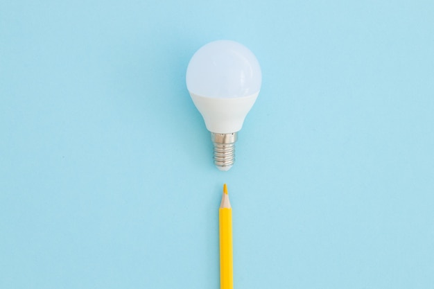 Lampada a LED e matita si trovano su uno sfondo blu pastello