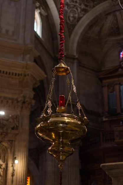 Lampada antica appesa al soffitto di una chiesa con un cordone rosso