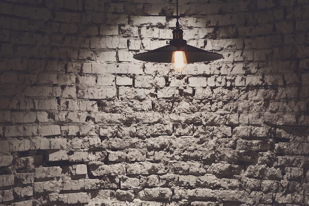 Lampada da parete e soffitto in mattoni grunge, copia spazio. Sfondo grigio ruvido, Hang lampadina illumina parte del lato