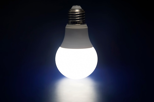 Lampada LED incandescente su sfondo blu scuro. Tecnologia ed elettricità moderne