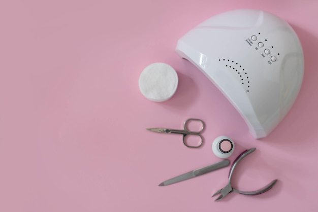 Lampada ultravioletta e strumenti per manicure su sfondo rosa Manicure con smalto gel