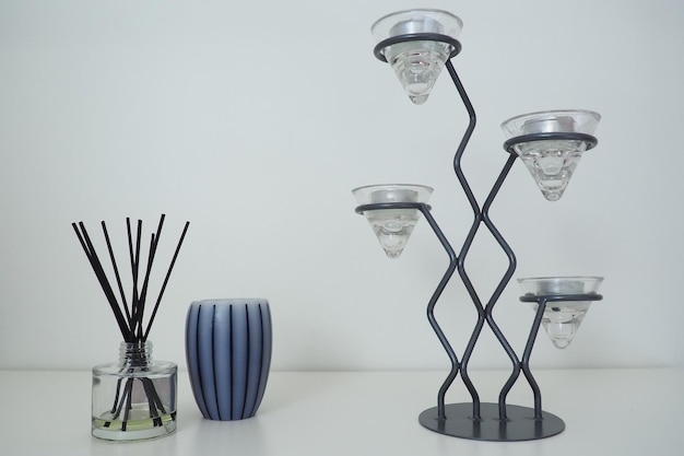 Lampadario alto in metallo con portacandele in vetro per piccole candele Sfondo bianco Bastoncini di incenso in un recipiente cubico di vetro con olio essenziale Decorazione d'interni Candela o vaso a strisce grigie profumate