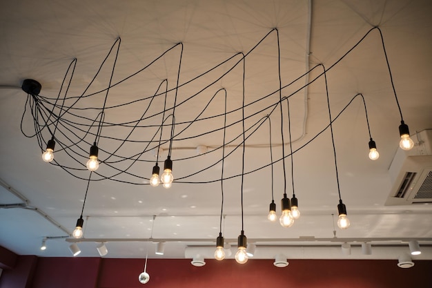 Lampadario insolito con singole lampadine a soffitto nell'accogliente caffè Le lampade illuminano un'ampia stanza