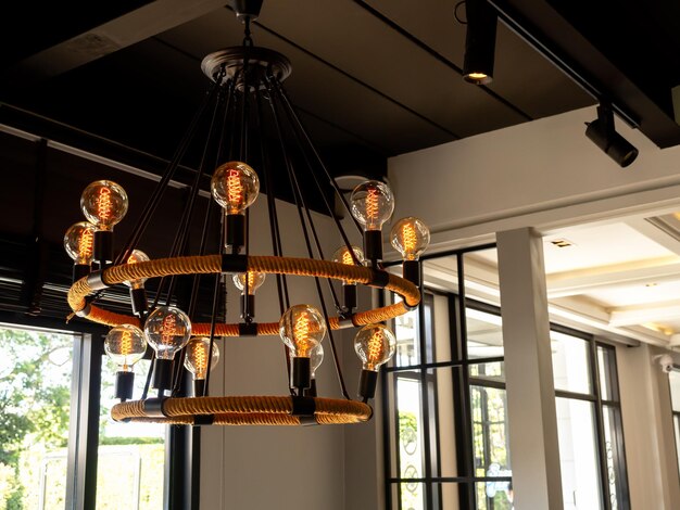 Lampadario moderno nel soggiorno vicino alla finestra di vetro plafoniera vintage in stile loft o lampadine appese al soffitto in legno edificio interno in stile loft interno Decorazione di illuminazione retrò