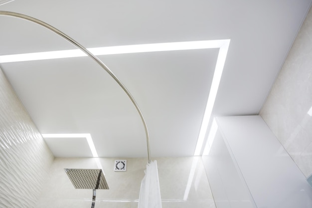 Lampade alogene su soffitto sospeso e costruzione di pareti a secco in una stanza vuota in un appartamento o in una casa Soffitto teso bianco e di forma complessa