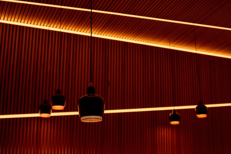 Lampade su fili lunghi davanti a una parete a strisce di legno elementi di illuminazione e interior design