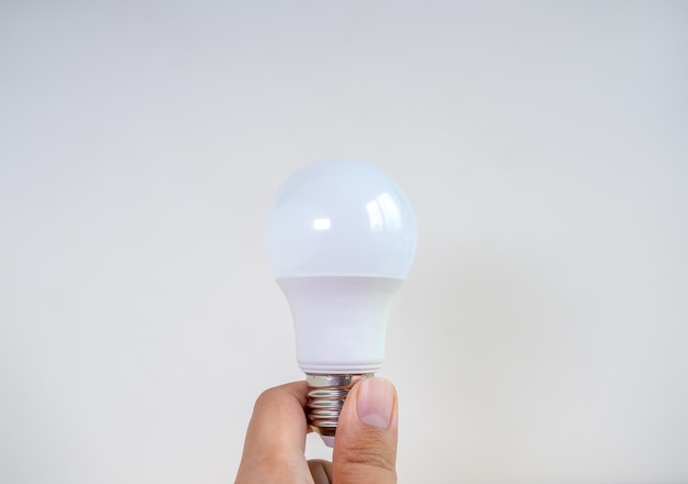 Lampadina a LED bianca moderna e pulita o lampada a risparmio tenuta a mano isolata su sfondo bianco Riciclare i concetti di pensiero delle idee di energia e creatività