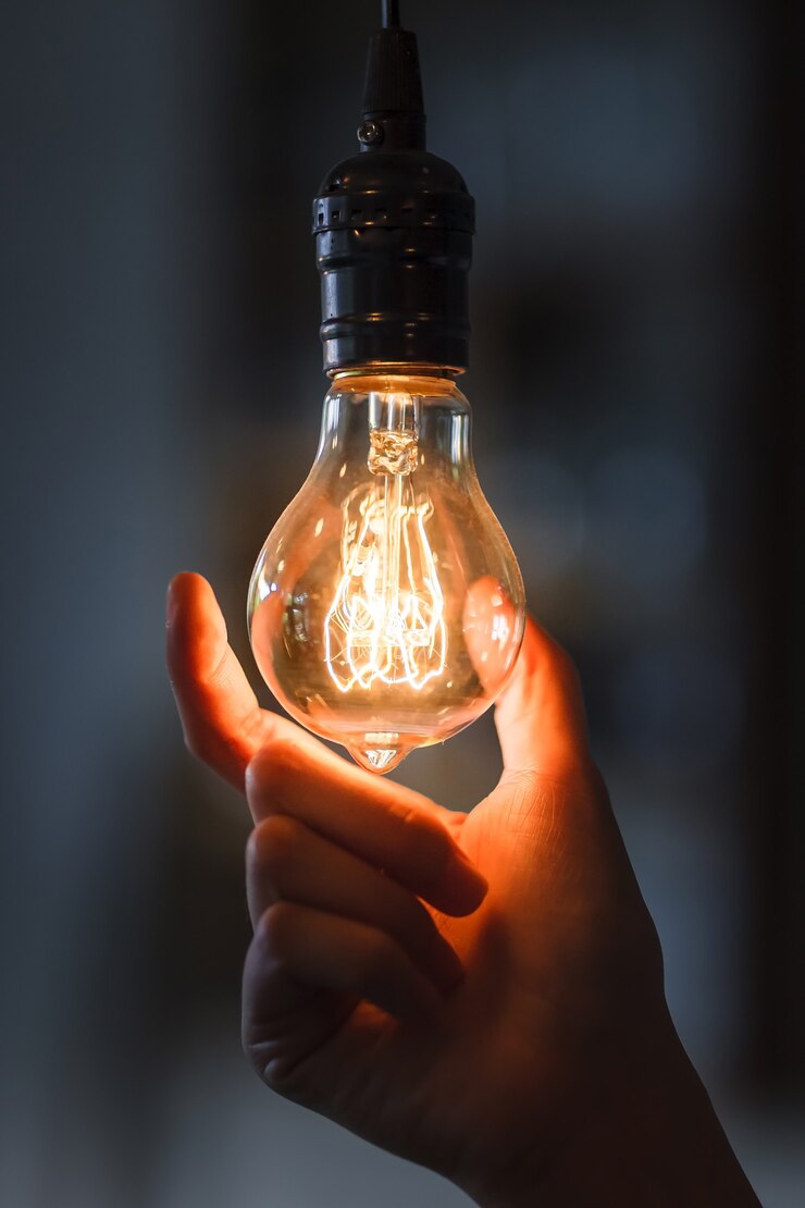 Foto lampadina con filamento tenuto in mano di donna