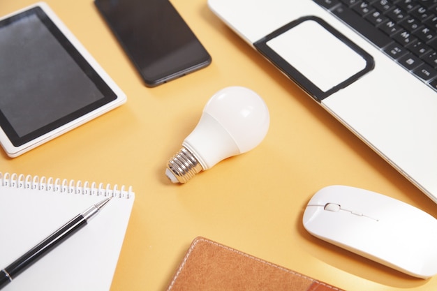 Lampadina con oggetti business su sfondo giallo.