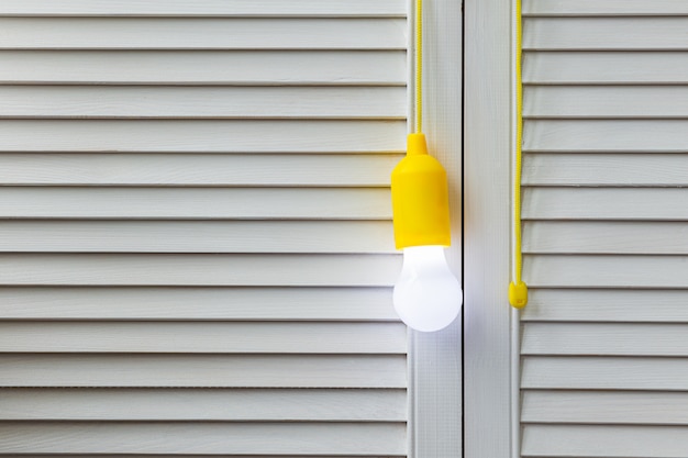 Lampadina di pizzo incandescente su fondo di legno bianco