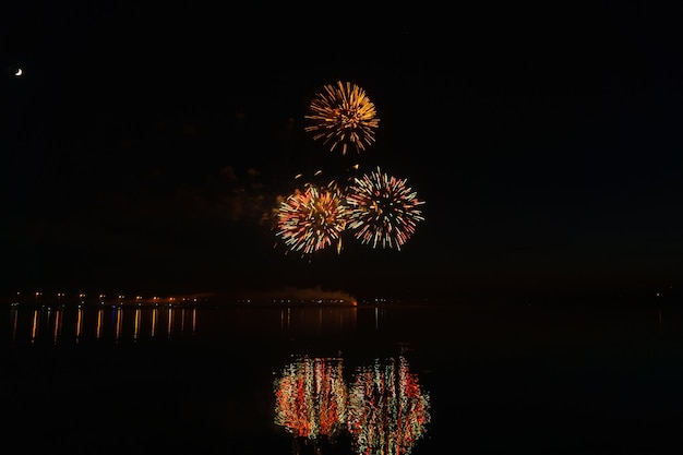 Lampi di saluto festivo sopra il fiume notturno si riflettono nell'acqua