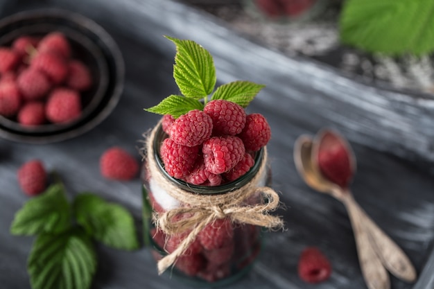 Lampone in un barattolo di vetro sulla tavola di legno scura. Concetto di cibo sano. Frutti di bosco biologici freschi