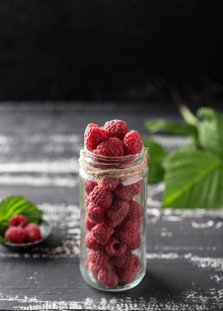 Lampone in un barattolo di vetro sulla tavola di legno scura. Concetto di cibo sano. Frutti di bosco biologici freschi