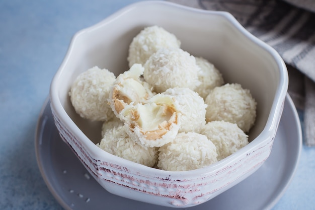 Lanci con le caramelle della noce di cocco sul fondo blu della tavola concreta. Avvicinamento