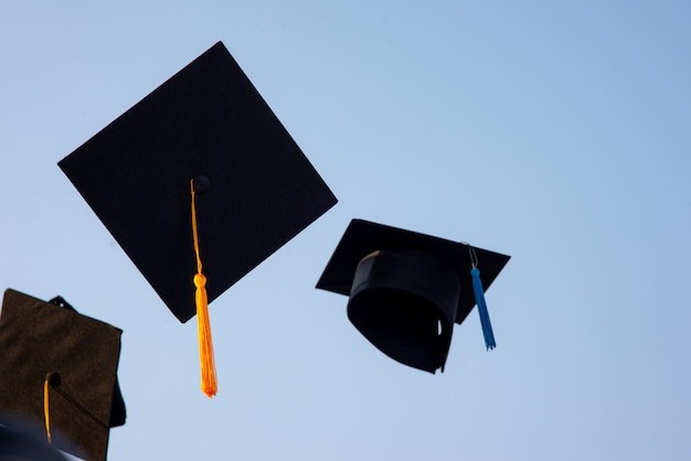 Lancia un cappello nero di laureati nel cielo.