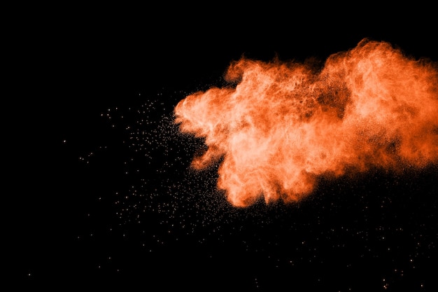 Lanciata esplosione di polvere di colore arancione su sfondo nero.