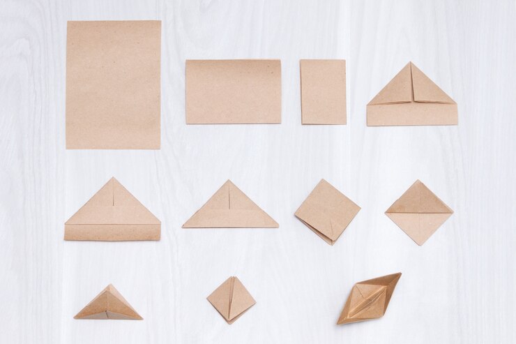 Photo langkah-langkah membuat perahu kertas origami di atas latar belakang kayu putih.