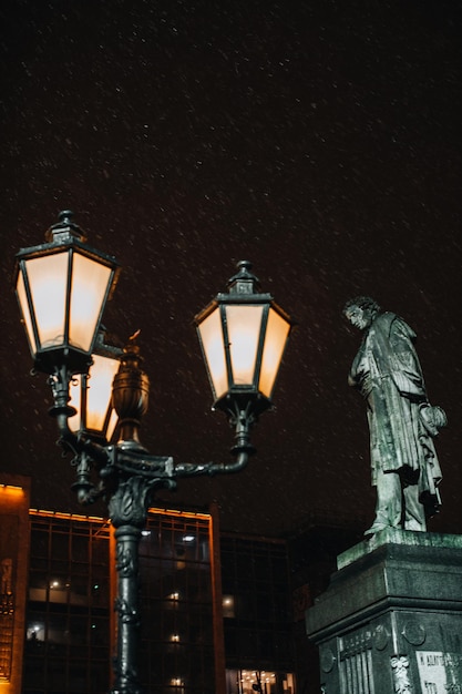 Lanterna accesa la sera e neve che cade Monumento al famoso poeta russo Alexander Pushkin
