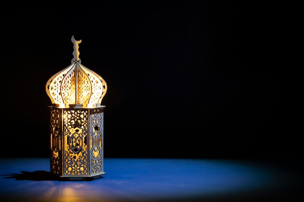 Lanterna araba ornamentale con candela accesa che brilla di notte e luci bokeh dorate luccicanti Cartellino di auguri festivo per il mese santo musulmano del Ramadan Kareem