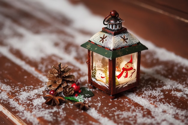 Lanterna di Natale con la candela sulla tavola di legno colorata marrone